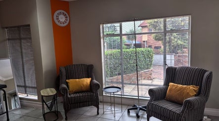 Relaxation area at NASIMISA: Health & Wellness Hub, Pretoria, Gauteng, ZA with striped chairs and orange pillows.
