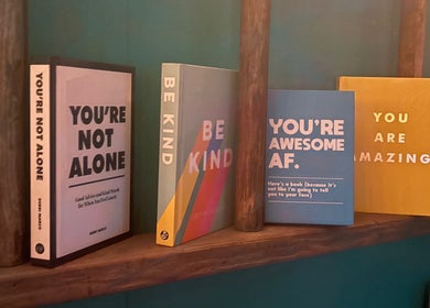 Motivational books on display at Velvet Tattoos, Dunsdale, England, GB, offering uplifting messages.