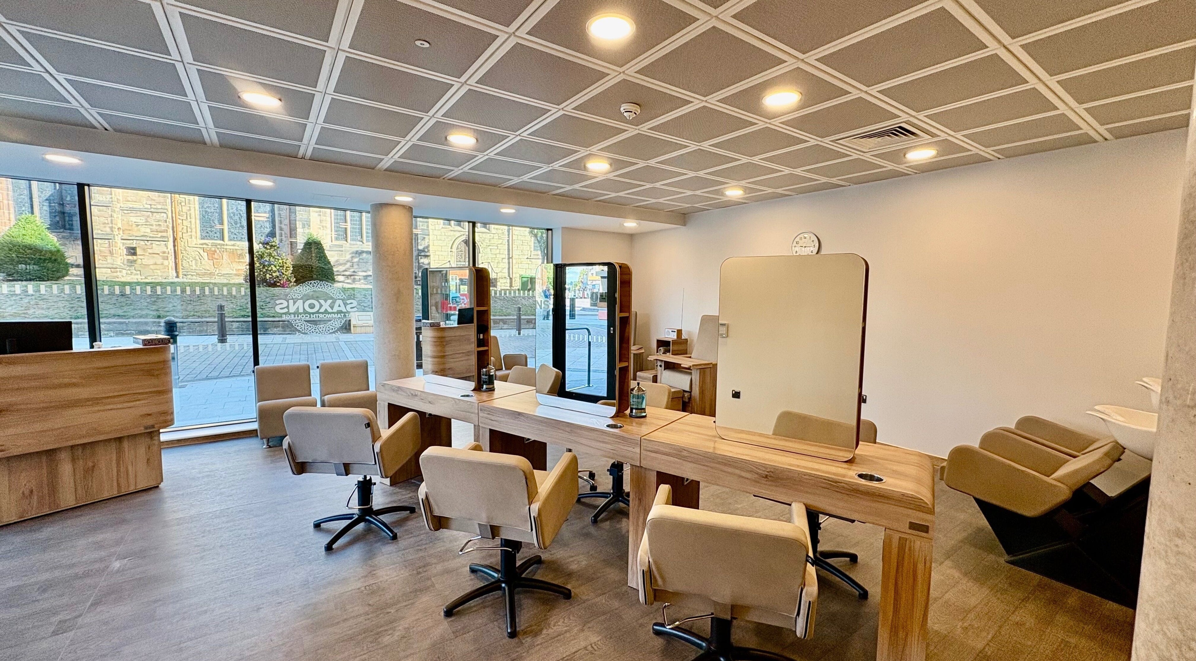 Bright salon interior at Saxons at Tamworth College, featuring stylish wooden workstations, Tamworth, England, GB.