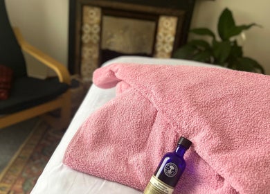 Relaxing pink towel and massage oil at Her Sanctuary Holistic Therapies, Leeds, England, GB, offering soothing treatments.