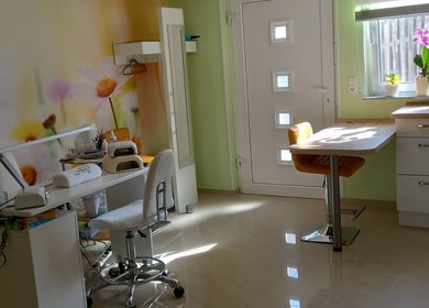 Innenraum von Studio Tatjana in Mühlacker, Baden-Württemberg, DE mit bunter Blütenwand und Nagelpflege-Ecke.