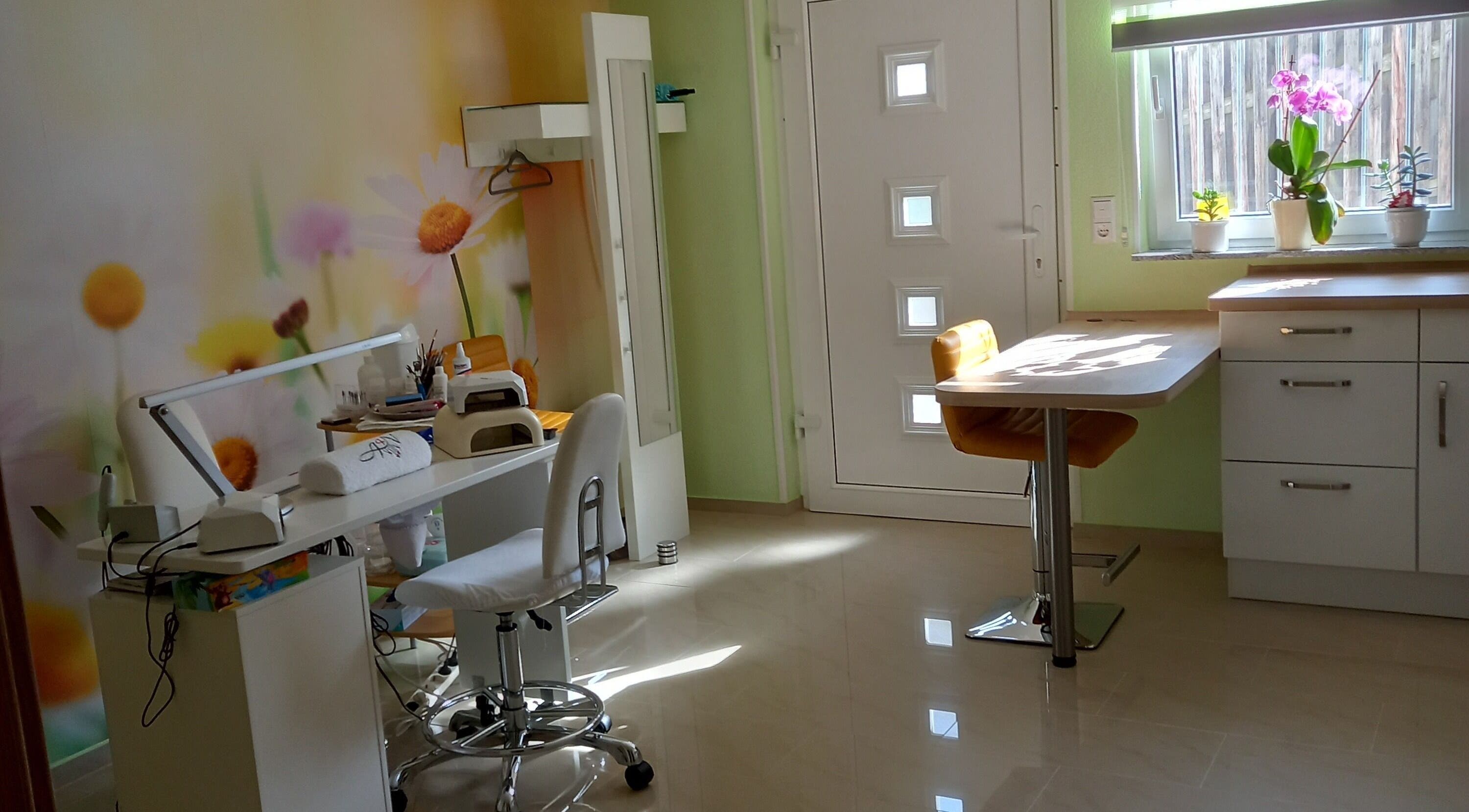 Innenraum von Studio Tatjana in Mühlacker, Baden-Württemberg, DE mit bunter Blütenwand und Nagelpflege-Ecke.