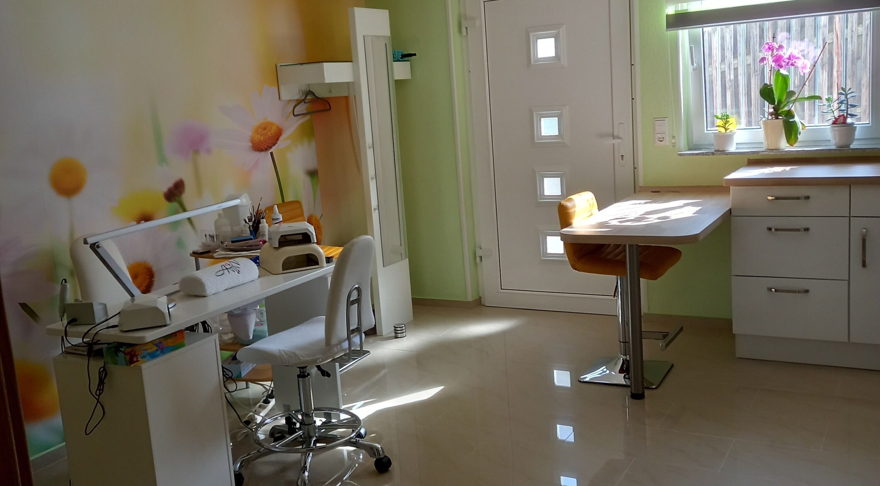 Innenraum von Studio Tatjana in Mühlacker, Baden-Württemberg, DE mit bunter Blütenwand und Nagelpflege-Ecke.