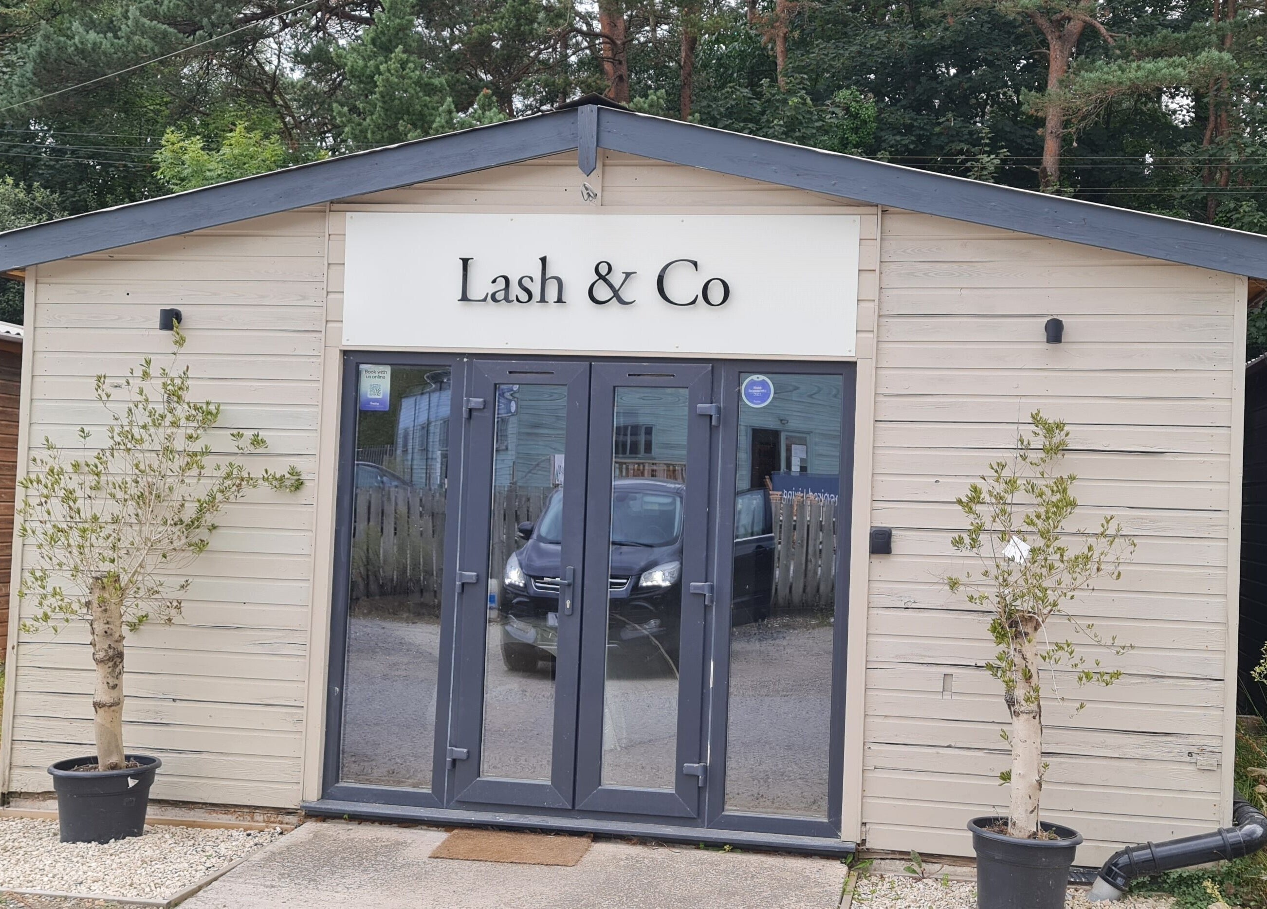 Charming exterior of Nails by Claire in Par, England, GB surrounded by trees, highlighting the serene venue.