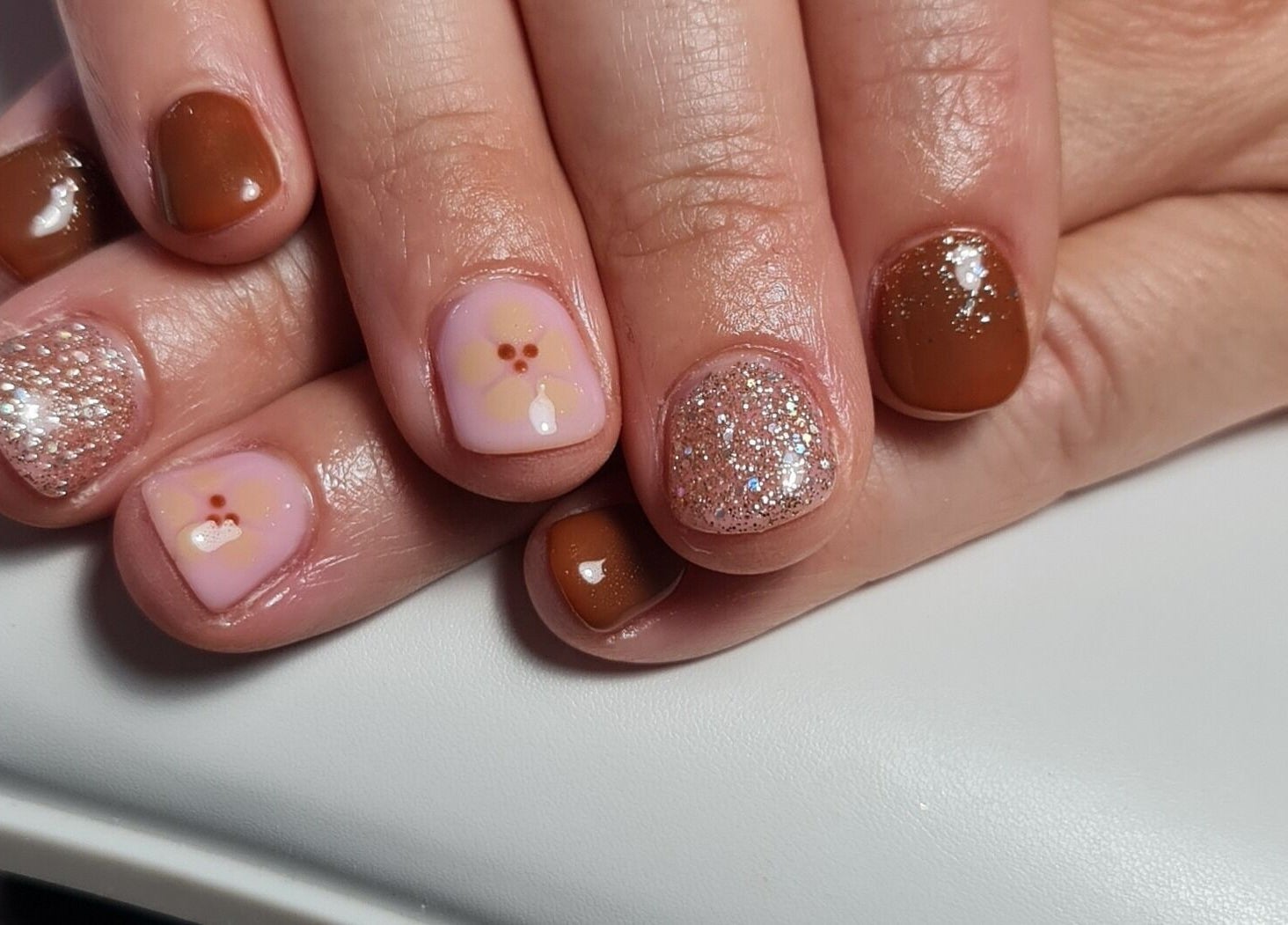 Stylish nail design with glitter and flowers at Nails by Claire, Par, England, GB.