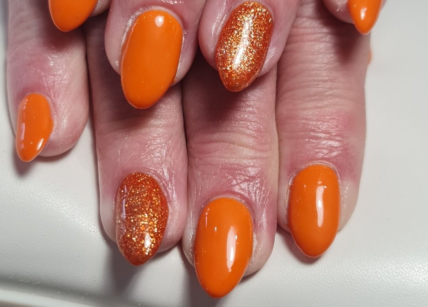 Bright orange and glitter nail art at Nails by Claire, Par, England, GB. Vibrant manicure showcase.