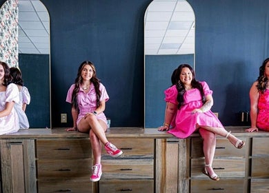 Four women in vibrant dresses at SG Stylez Hair Salon, Wills Point, Texas, US, seated by tall mirrors.
