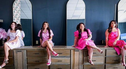 Four women in vibrant dresses at SG Stylez Hair Salon, Wills Point, Texas, US, seated by tall mirrors.
