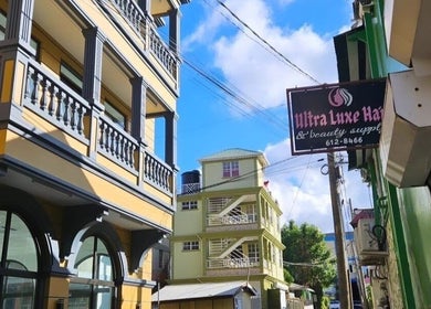 Colorful buildings near The Beauty Cuisine, Roseau, Saint George Parish, DM under a bright blue sky.