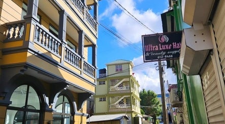 Colorful buildings near The Beauty Cuisine, Roseau, Saint George Parish, DM under a bright blue sky.