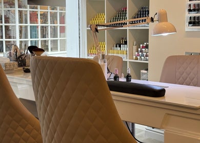 Elegant manicure station at Nhi's Nails in Truro, England featuring sleek chairs and organized nail polish displays.