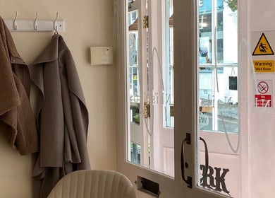 Warm coats hang by the entrance at Nhi's Nails, Truro, England, GB, creating a welcoming atmosphere.