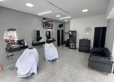 Interior da BARBEARIA EMUNÁH em São Paulo, São Paulo, BR. Cadeiras e espelhos iluminados em ambiente elegante.