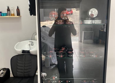 Interior da BARBEARIA EMUNÁH em São Paulo com produtos em estante e cadeira de barbeiro.