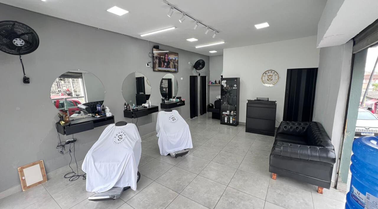 Interior moderno da BARBEARIA EMUNÁH em São Paulo, São Paulo, BR com poltronas e espelhos elegantes.