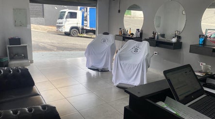 Interior moderno da BARBEARIA EMUNÁH em São Paulo com cadeiras de barbeiro e espelhos grandes.