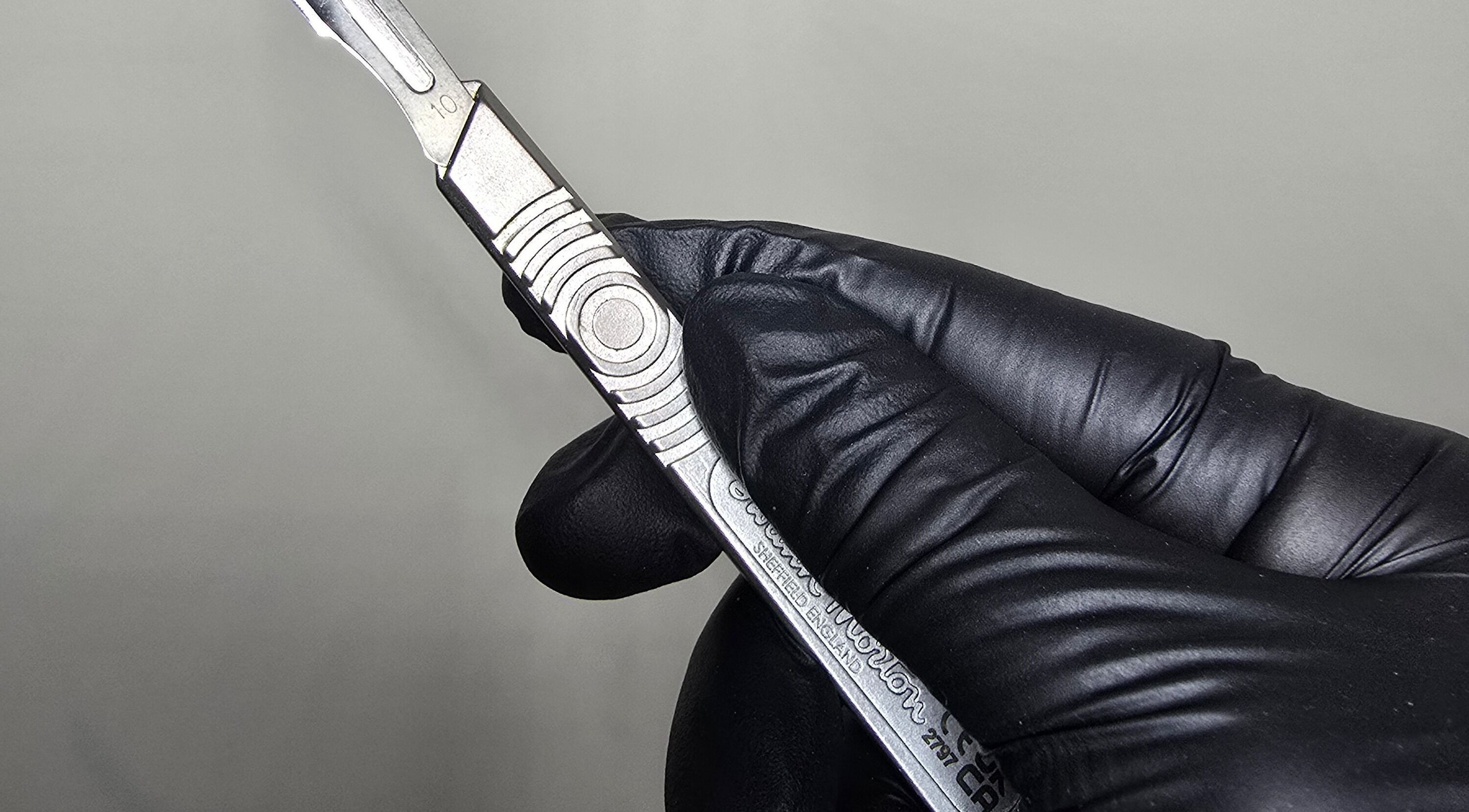 Close-up of a scalpel held in gloved hand at Glam Studio, Cape Town, Western Cape, ZA.