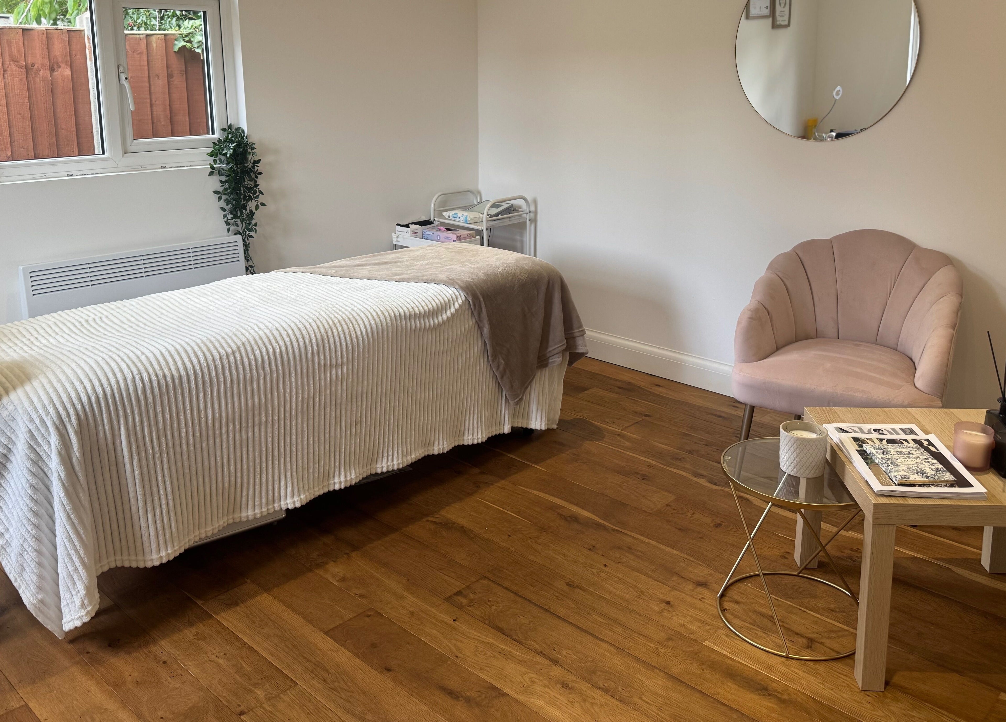 Calm treatment room at Arch & Lash co. in Guildford, England, featuring a massage bed and cozy seating.