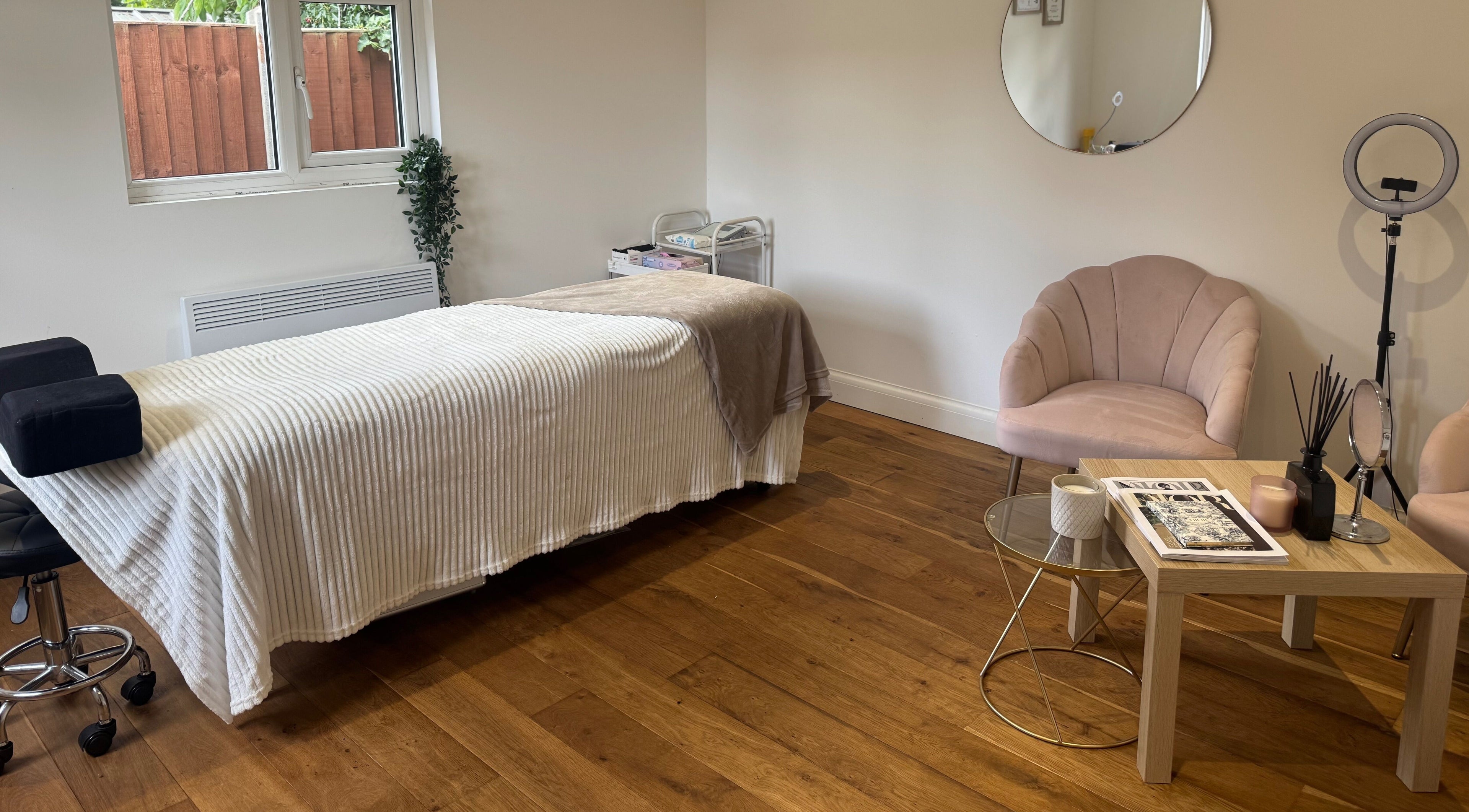 Calm treatment room at Arch & Lash co. in Guildford, England, featuring a massage bed and cozy seating.