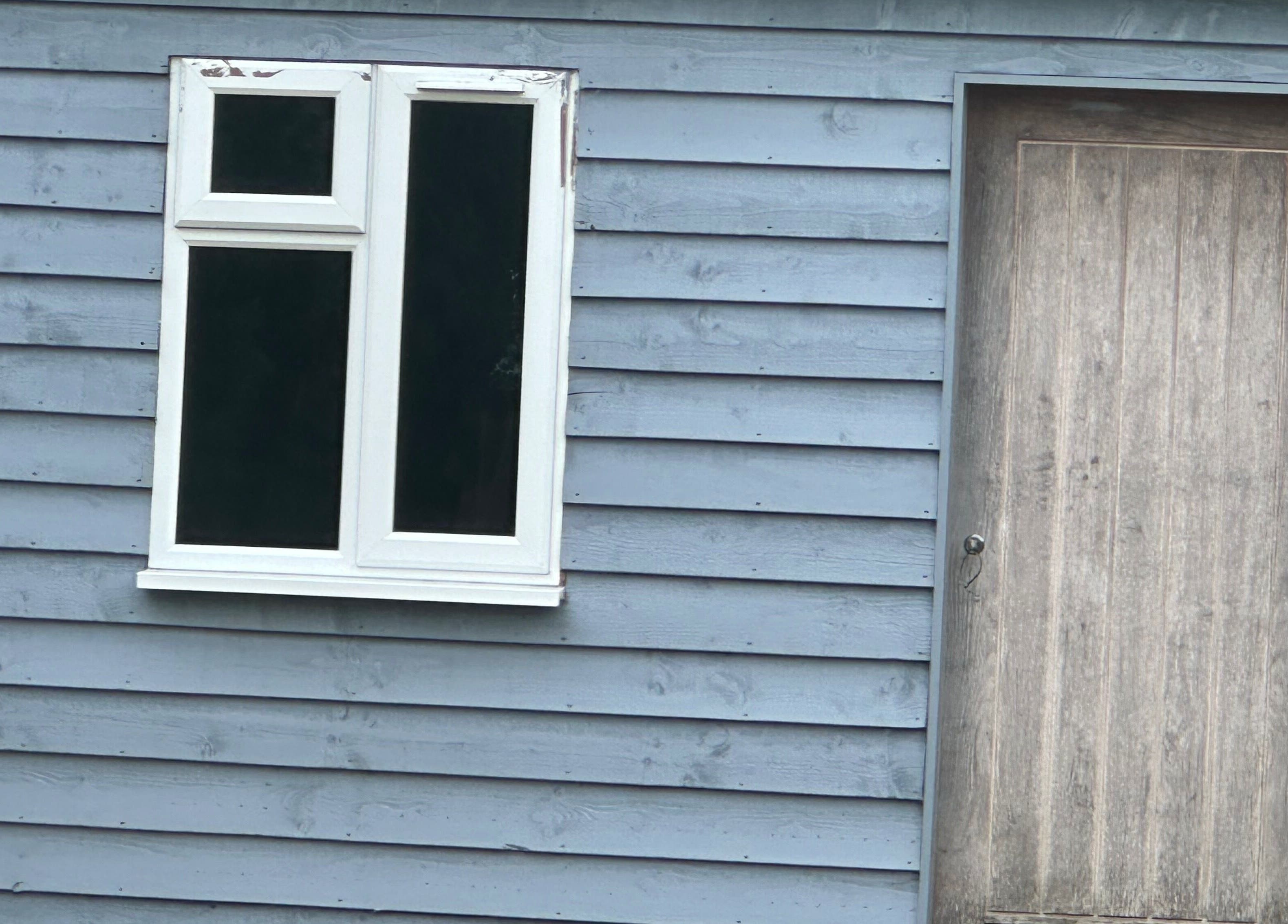Blue wooden facade of Arch & Lash co. in Guildford, England, GB with window and door.