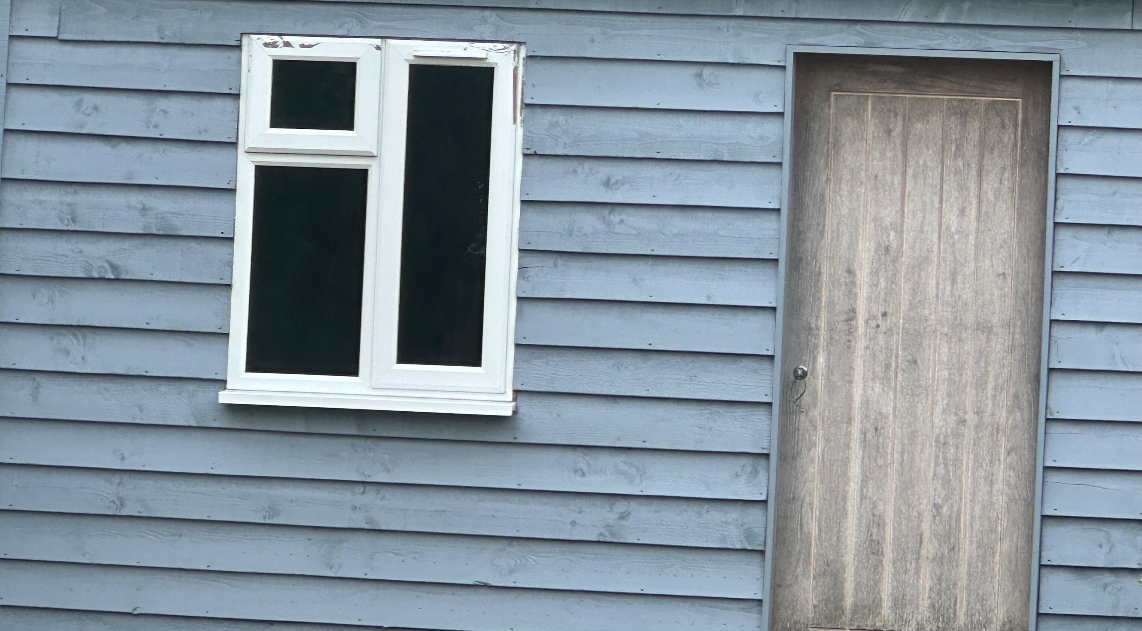 Blue wooden facade of Arch & Lash co. in Guildford, England, GB with window and door.