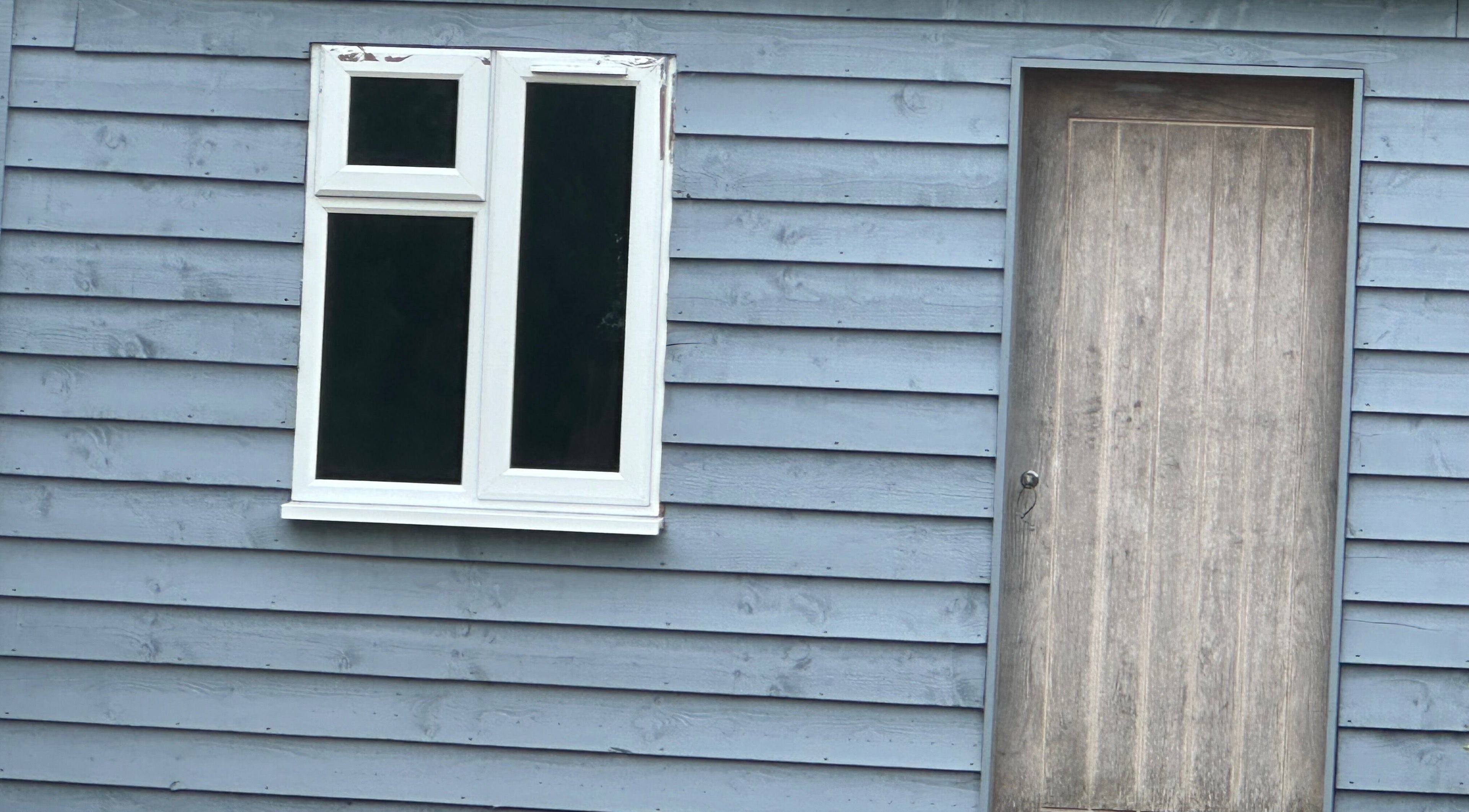 Blue wooden facade of Arch & Lash co. in Guildford, England, GB with window and door.