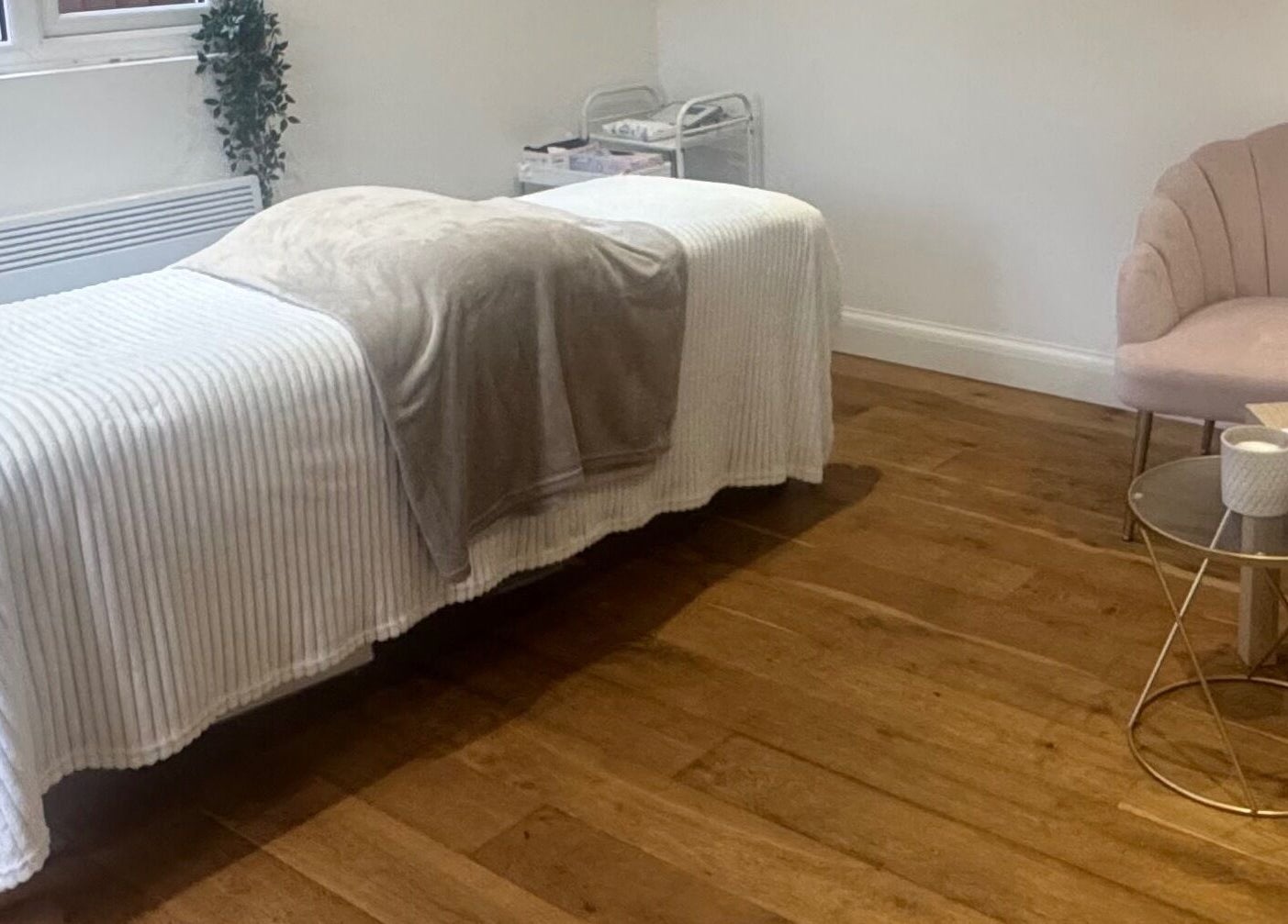 Cozy treatment area at Arch & Lash co. in Guildford, England, GB with plush chair and massage bed.