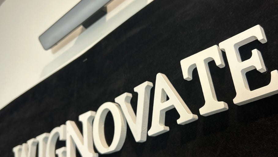 Close-up of WIGNOVATE sign at Ocho Rios, JM, showcasing elegant white lettering on a dark background.