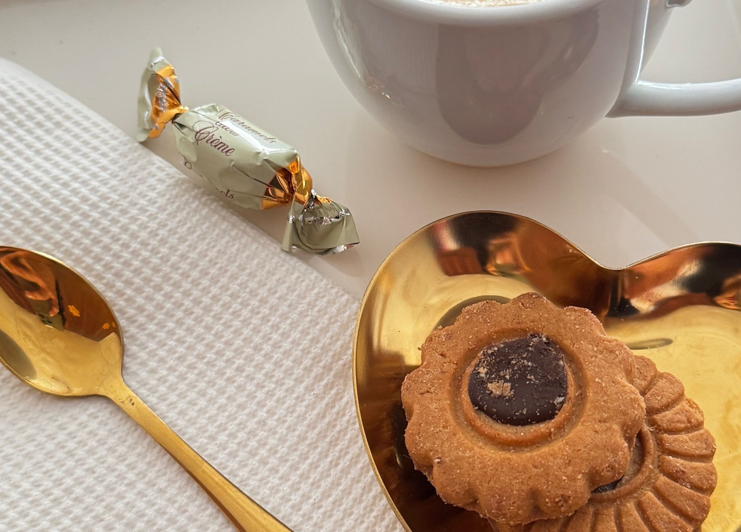 Detalhe de café com biscoito e colher dourada em Ma Belle Estetica, Lisboa, Lisboa, PT.