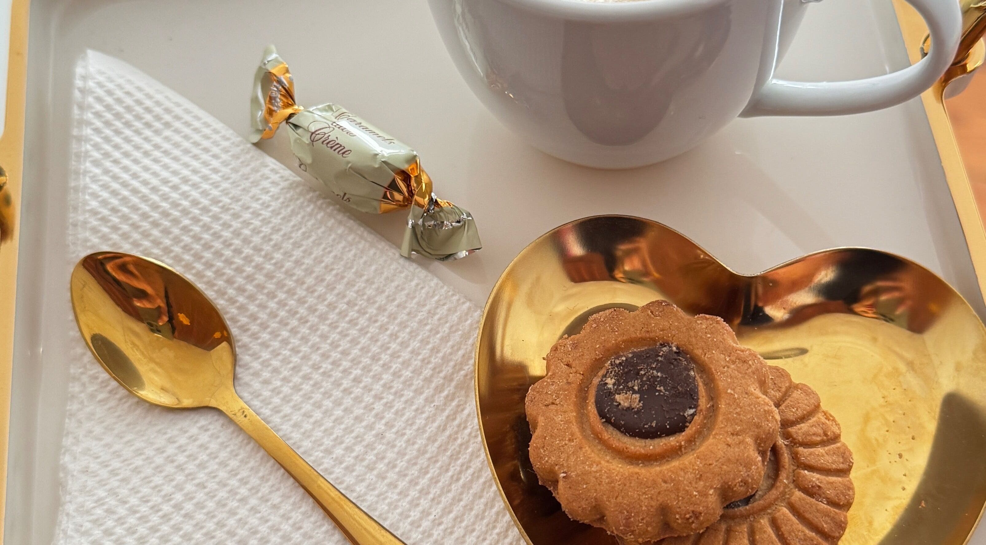 Detalhe de café com biscoito e colher dourada em Ma Belle Estetica, Lisboa, Lisboa, PT.