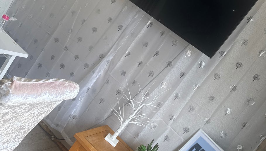 Elegant decor at SWbeautyx, Dunmow, England, GB featuring a white tree sculpture and patterned curtain.