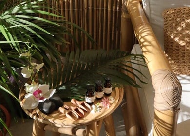 زاوية مريحة في VS Salon, الرياض, منطقة الرياض, SA تضم كرسي خشبي وطاولة مزدانة بالنباتات والزيوت.