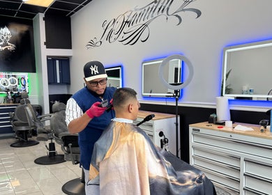Professional barber styling hair at La Familia Barbershop, Chicago, Illinois, US.