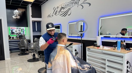 Professional barber styling hair at La Familia Barbershop, Chicago, Illinois, US.