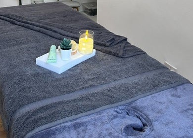 Luxurious treatment bed at Wellness by Mariana, Southampton, England, GB, with candles and succulents.