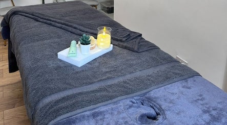 Luxurious treatment bed at Wellness by Mariana, Southampton, England, GB, with candles and succulents.