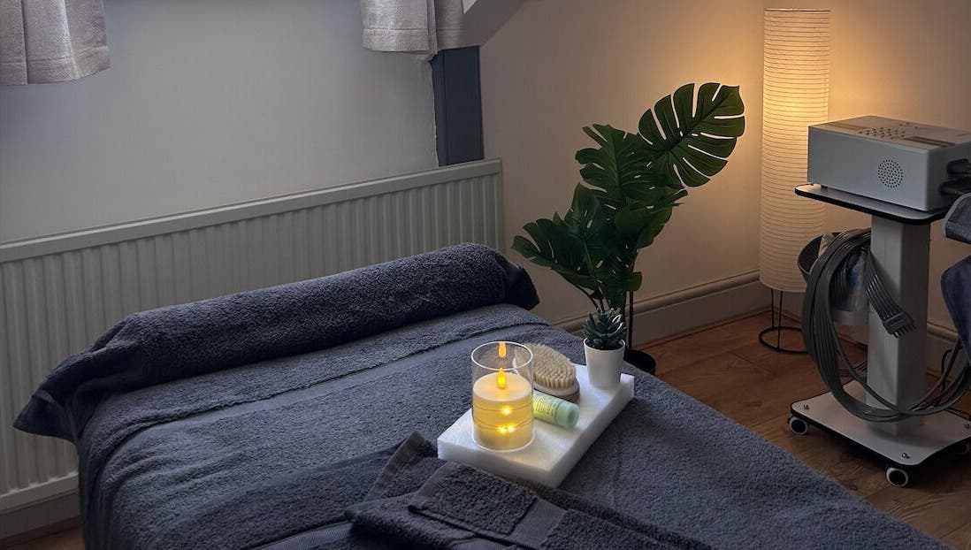 Cozy massage room at Wellness by Mariana, Southampton, England, GB, featuring candles and plush towels.