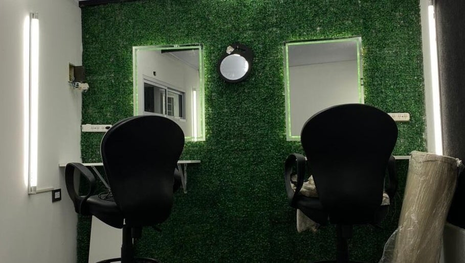 Interior moderno en Alex Wacker, José Marmol, con sillas negras y pared verde iluminada.