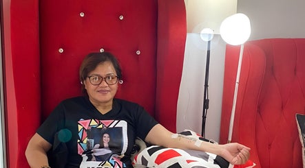 Guest relaxes in plush red chair at Glazed Beauty Lounge, Antipolo City, Calabarzon, PH.