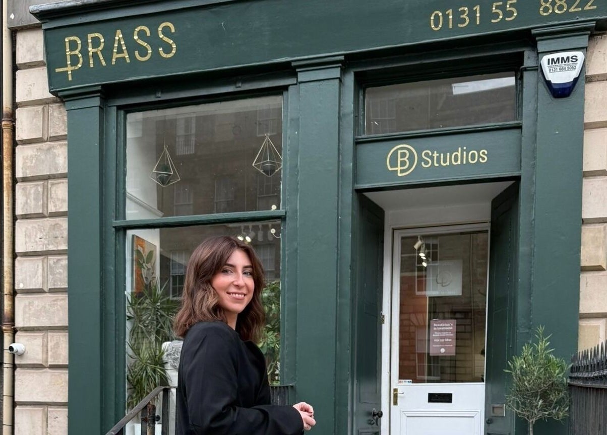 Entrance of Mitts Nails in Edinburgh, Scotland, GB, showcasing stylish green exterior with smiling visitor.