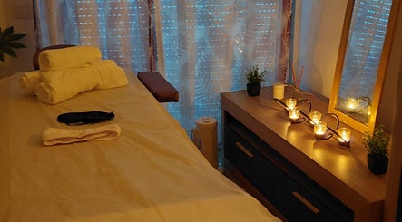 Sala de massagem relaxante em Studio Alex Rafael, Faro, Faro, PT, com toalhas e velas iluminadas.