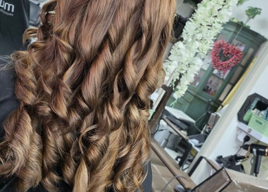 Stylish curled hairstyle at Stained Beauty Co salon in Arnold, England, GB with flower decor.