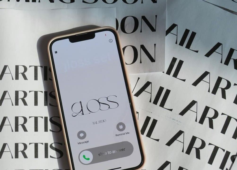 Phone screen showcasing Gloss Sets by Cay, Gqeberha, Eastern Cape, ZA with nail artist background.