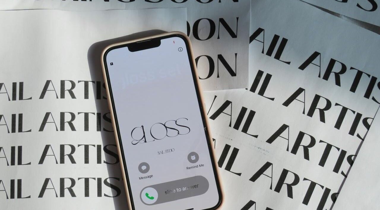 Phone screen showcasing Gloss Sets by Cay, Gqeberha, Eastern Cape, ZA with nail artist background.