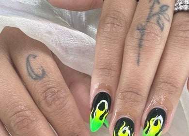Vibrant flame nail art at Nailvana, Cincinnati, Ohio, US, showcasing intricate black and green designs.