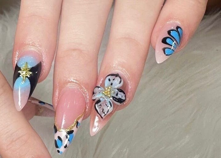 Intricate blue and floral nail art at Nailvana, Cincinnati, Ohio, US, showcasing creative manicure designs.