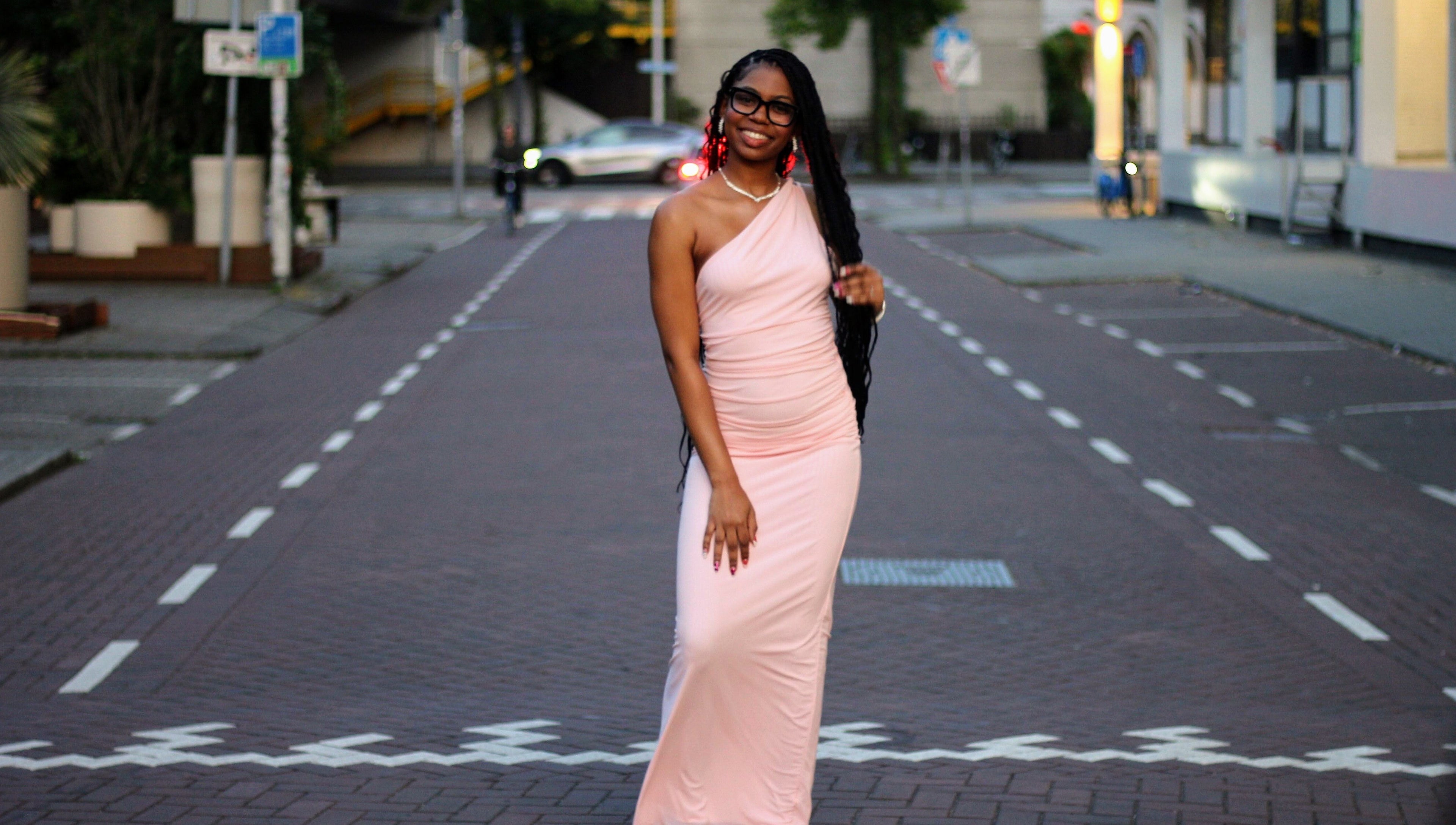 Elegant woman in pink dress on a city street at Nevia Glam, NL.