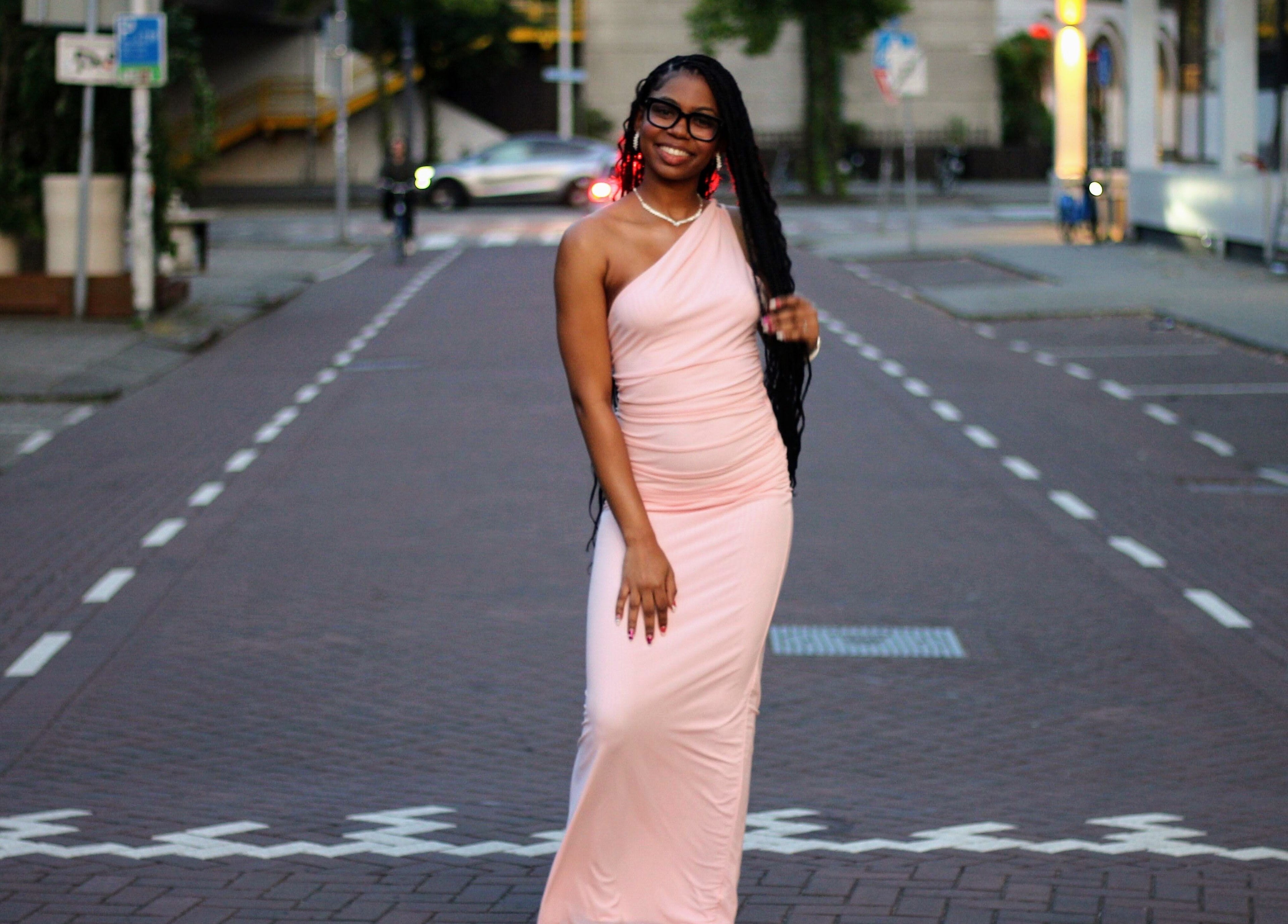 Elegant woman in pink dress on a city street at Nevia Glam, NL.