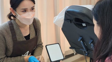 A specialist at AOh Beauty in Kowloon, HK, attentively consulting a client with a mirror in hand.