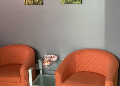 Inviting seating area at Lido Massage in Gainesville, Georgia, US featuring orange chairs and elegant decor.